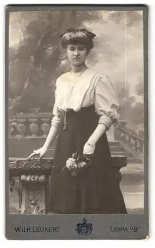 Fotografie Wilhelm Leukert, Leipa i. B., Brückenstrasse, Schöne Dame mit Haarschleife, Spitzenhandschuhen u. Rose