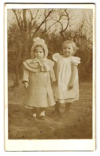 Fotografie E. Jänisch, Ort unbekannt, Mädchen in Winterkleidung neben Mädchen in ärmellosem Kleid
