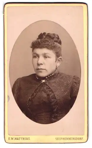 Fotografie E. W. Matthias, Seifhennersdorf, Dame im schwarzen Kleid mit Hochsteckfrisur