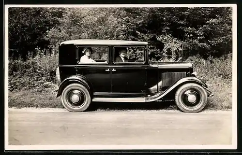 Foto-AK Auto, Mann und Frau in einem schwarzen KFZ mit Ersatzreifen am Kofferraum