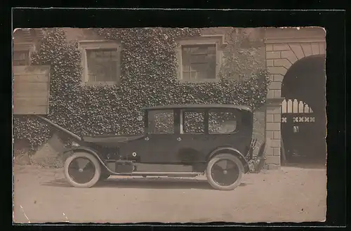 Foto-AK Auto, Schwarzes KFZ mit weissen Reifen vor einer weinbewachsenen Wand