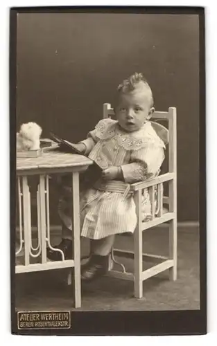 Fotografie Atelier Wertheim, Berlin, Rosenthalerstrasse, Kleines Kind im hellen Kleidchen auf einem Stuhl am Tisch