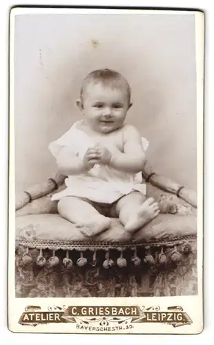 Fotografie C. Griesbach, Leipzig, Bayerschestrasse 30, Lachendes Baby im Strampler auf einem Sitzmöbel