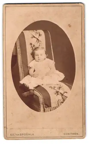 Fotografie Ed. von Spoenla, Coethen, Leopoldstr. 9, Kleinkind im Rüschenkleid in entspannter Pose auf einem Stuhl