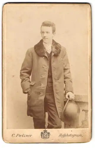 Fotografie C. Pietzner, Wien, Mariahilferstr. 1b, Junger Mann in einer Jacke mit Pelzkragen, Melone in der Hand