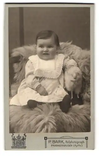 Fotografie P. Bark, Frankenhausen, Kleines Mädchen im weissen Kleid, grinsend mit ihrem Spielzeugschaf