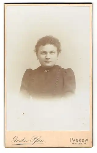 Fotografie Gustav Pfau, Pankow, Kreuzstr. 16, Mädchen mit lockigem Haar im schwarzen Kleid mit Zierknopfreihen