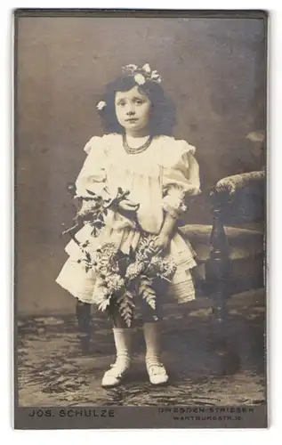 Fotografie Jos. Schulze, Dresden-Striesen, Wartburgstr. 10, Kleines Mädchen im weissen Kleid mit Blume im Haar