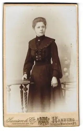 Fotografie Samson & Co., Hamburg, Grosse Bleichen 31, Junge schöne Frau im schwarzen geknöpften Kleid mit Silberbrosche
