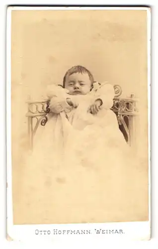 Fotografie Otto Hoffmann, Weimar, Schröterstr. 31, Niedliches Baby im weissen Kleid schaut müde an der Kamera vorbei