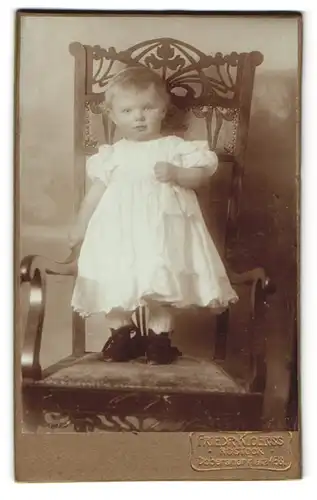 Fotografie Friedr. Kloerss, Rostock, Doberanerplatz 158, Süsses Kleinkind im weissen Kleid mit runden Bäckchen