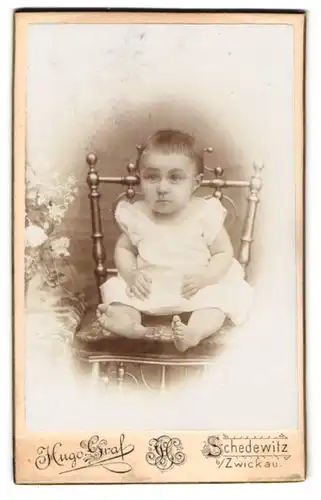 Fotografie Hugo Graf, Schedewitz, Hauptstr. 71, Niedliches Baby im weissen Kleid mit erwartungsvollem Blick