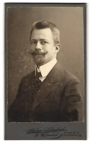 Fotografie R. Westendorp, Hagen, Elberfelderstr. 49, Junger Herr im schwarzen Anzug mit gezwirbelten Schnurrbart