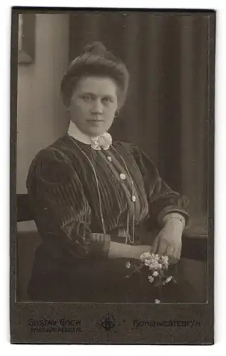 Fotografie Gustav Gock, Hohenwestedt i. H., Bürgerliche Dame mit Blütenelement am Kragen und Blume in der Hand