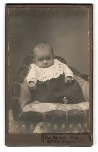 Fotografie Max Rother, Nossen, Waldheimerstr. 29, Baby mit abwartendem Blick im Kleid mit weissem Zierkragen