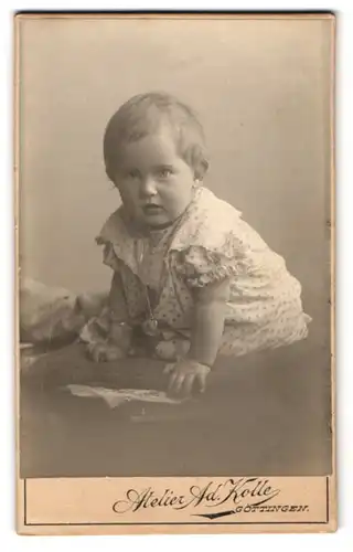 Fotografie Ad. Kolle, Göttingen, Prinzenstr. 18, Kleinkind im gepunkteten Kleid mit einem herzförmigen Medaillon