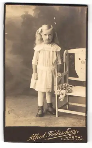 Fotografie Alfred Fritzsching, Löbau, Gartenstr., Kleines Mädchen im weissen Kleid mit einer Schleife im Haar