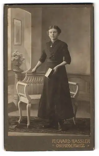 Fotografie Richard Bassler, Oberoderwitz, Junge Dame mit einem Mittelscheitel im schwarzen Kleid, ein Buch in der Hand