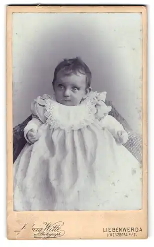 Fotografie Ludwig Witte, Liebenwerda, Bahnhofstr. 4, Kleinkind im langen weissen Kleid mit grossen Augen