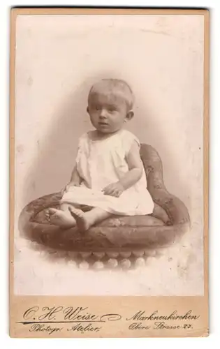 Fotografie O. H. Weise, Markneukirchen, Obere Strasse 27, Kleines Kind im Kleid mit nackigen Füssen