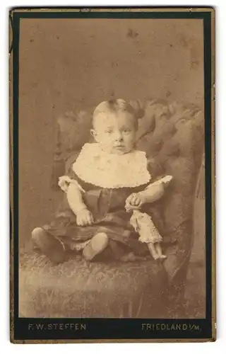 Fotografie F. W. Steffen, Friedland in Mecklbg., Süsses Kleinkind im Kleid mit Puppe