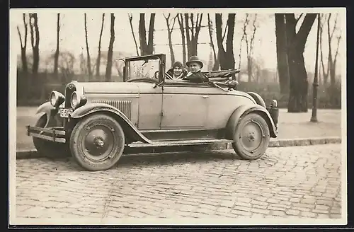 Foto-AK Auto Chevrolet AB-National (1928), Junges Paar lächelt stolz aus ihrem KFZ heraus