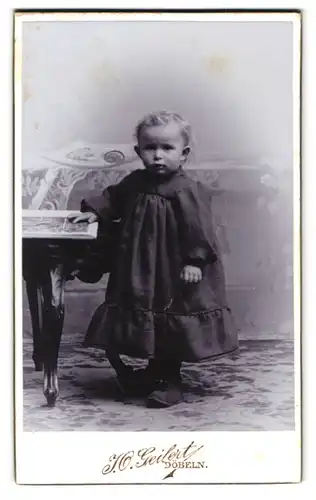 Fotografie J. O. Geilert, Döbeln, Schiesshausstr. 15, Kleines Kind im Kleid mit Bilderbuch