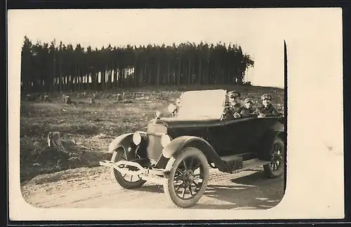 Foto-AK Auto AGA (1924 /25), Mann fährt mit zwei Damen am abgeholzten Wald vorbei