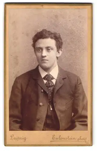 Fotografie Eulenstein, Leipzig, Zeitzer-Str. 30, Junger Mann im schwarzen Anzug mit gepunkteter Krawatte und müdem Blick