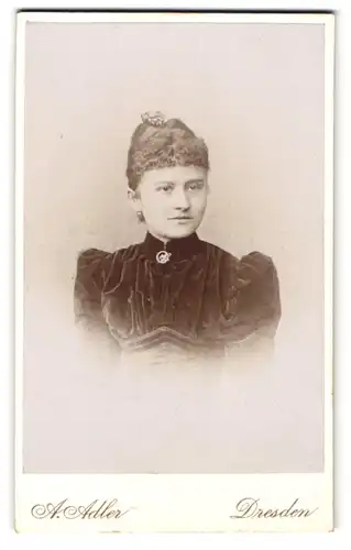 Fotografie A. Adler, Dresden, Victoriastr. 21, Junge Dame im schwarzen Samtkleid mit heller Brosche und lockigem Haar