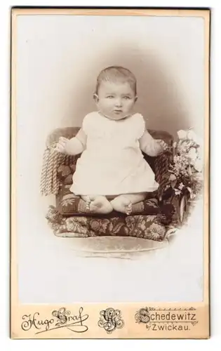 Fotografie Hugo Graf, Schedewitz, Hauptstr. 71, Niedliches Baby im weissen Kleid hebt schmollend die Händchen