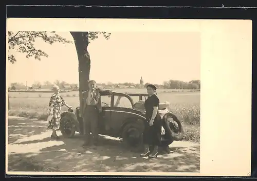 Foto-AK Auto DKW (1935), Familie mit jugendlicher Tochter am KFZ, unter einem Baum geparkt
