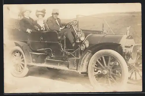 Foto-AK Auto Thomas Flyer (1909), Herr chauffiert zwei elegante Damen