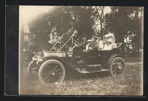 Foto-AK Auto Overland (1911), Fein gekleidete Familie parkt auf einer Wiese
