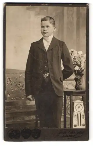 Fotografie Fritz Ette, Eisleben, Bahnhofstr. 18, Junger Bursche im schwarzen Anzug mit Anstecknadel und Krawatte