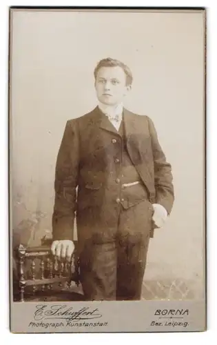 Fotografie E. Schuffert, Borna, am Bahnhof, Junger schöner Mann im schwarzen Anzug mit Hand an der Hosentasche