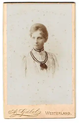 Fotografie A. Gäbel, Westerland, Junge schöne Dame im hellen Kleid mit schwarzer Schleife und glänzenden Augen