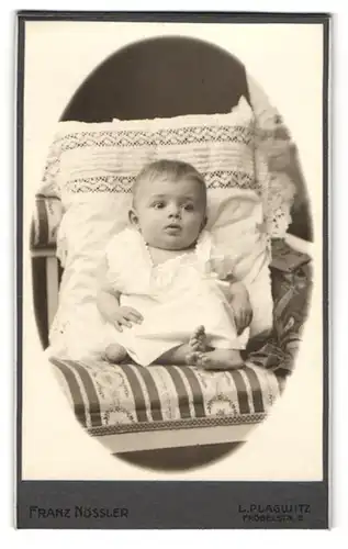 Fotografie Franz Nössler, Leipzig-Plagwitz, Fröbelstr. 8, Süsses Baby im weissen Kleid lehnt gegen ein grosses Kissen