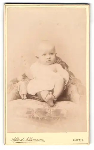 Fotografie Alfred Naumann, Leipzig, Dorotheenstr., Niedliches Baby Janna im weissen Kleid mit Puppe auf einem Sessel