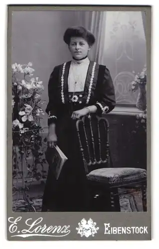 Fotografie E. Lorenz, Eibenstock, Junge Dame im schwarzen Kleid mit weissem Muster und Zeitschrift am Lächeln