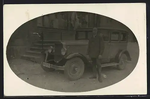 Foto-AK Auto Graham-Paige (1928), Junger Mann an einem zweifarbigen Fahrzeug vor einem Kleidungsgeschäft