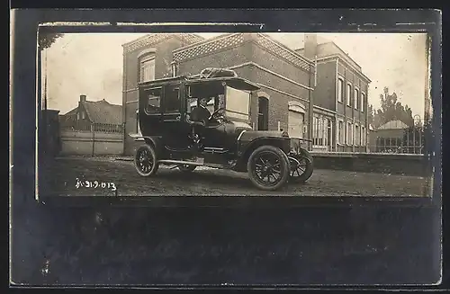 Foto-AK Auto Peugeot (1912), Junger Mann im schwarzen Fahrzeug vor einem Backstein-Gebäude