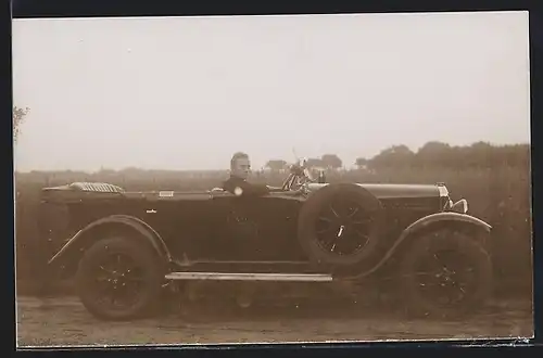 Foto-AK Auto Loreley U12 (1927), Junger Mann im polierten schwarzen Cabrio an einem Feld