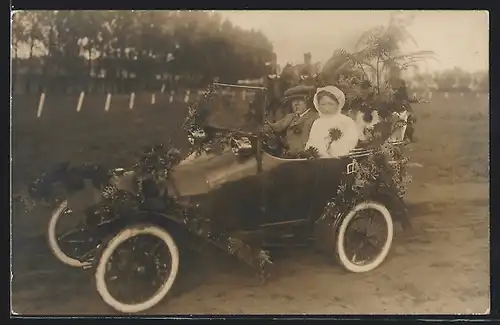 Foto-AK Auto Peugeot Bebe (1913), Ehepaar im reich mit Blumen geschmückten, kompakten KFZ