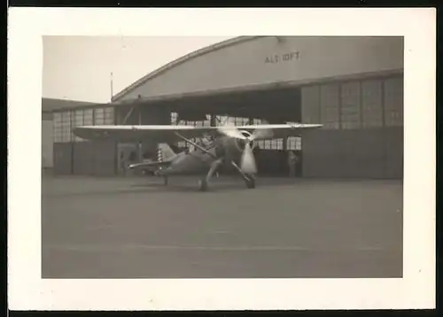 Fotografie Machi's Studio, Flugzeug Hochdecker Propellermaschine mit laufendem Motor vor einem Hangar, USA 1939