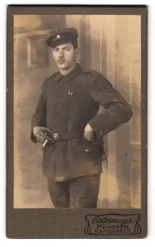 Fotografie Ostermayr, München, Soldat in schlichter Uniform mit Zigarette in der Hand