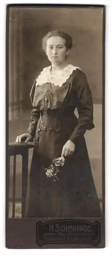 Fotografie H. Schmorrde, Herrnhut-Bernstadt, Junge Frau im Kleid mit weissem Zierkragen und Blumen in der Hand