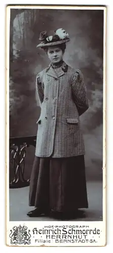 Fotografie Heinrich Schmorrde, Herrnhut, Junge Frau im karierten Mantel und schwarzen Rock mit auffälligem Hut