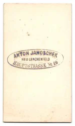 Fotografie Anton Janoschek, Neulerchenfeld, Dame im Kleid mit Haube und Fotoalbum in der Hand vor einer Studiokulisse