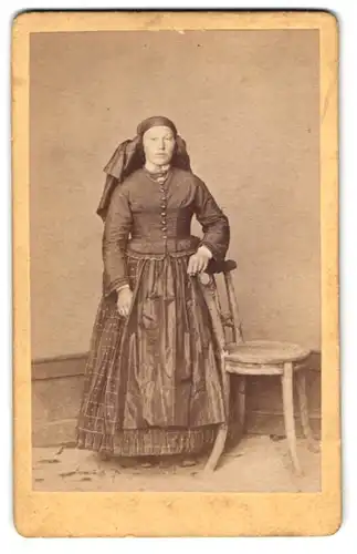 Fotografie M. Wild. Ort unbekannt, junge Frau im Trachtenkleid mit Schürze posiert im Atelier